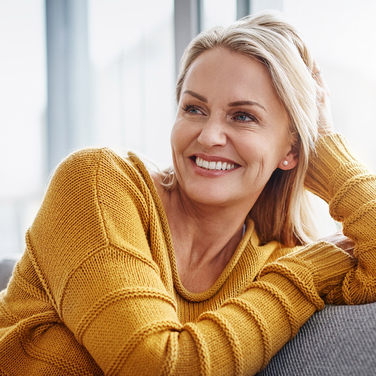 Boston Sculptra patient model smiling sitting on a couch