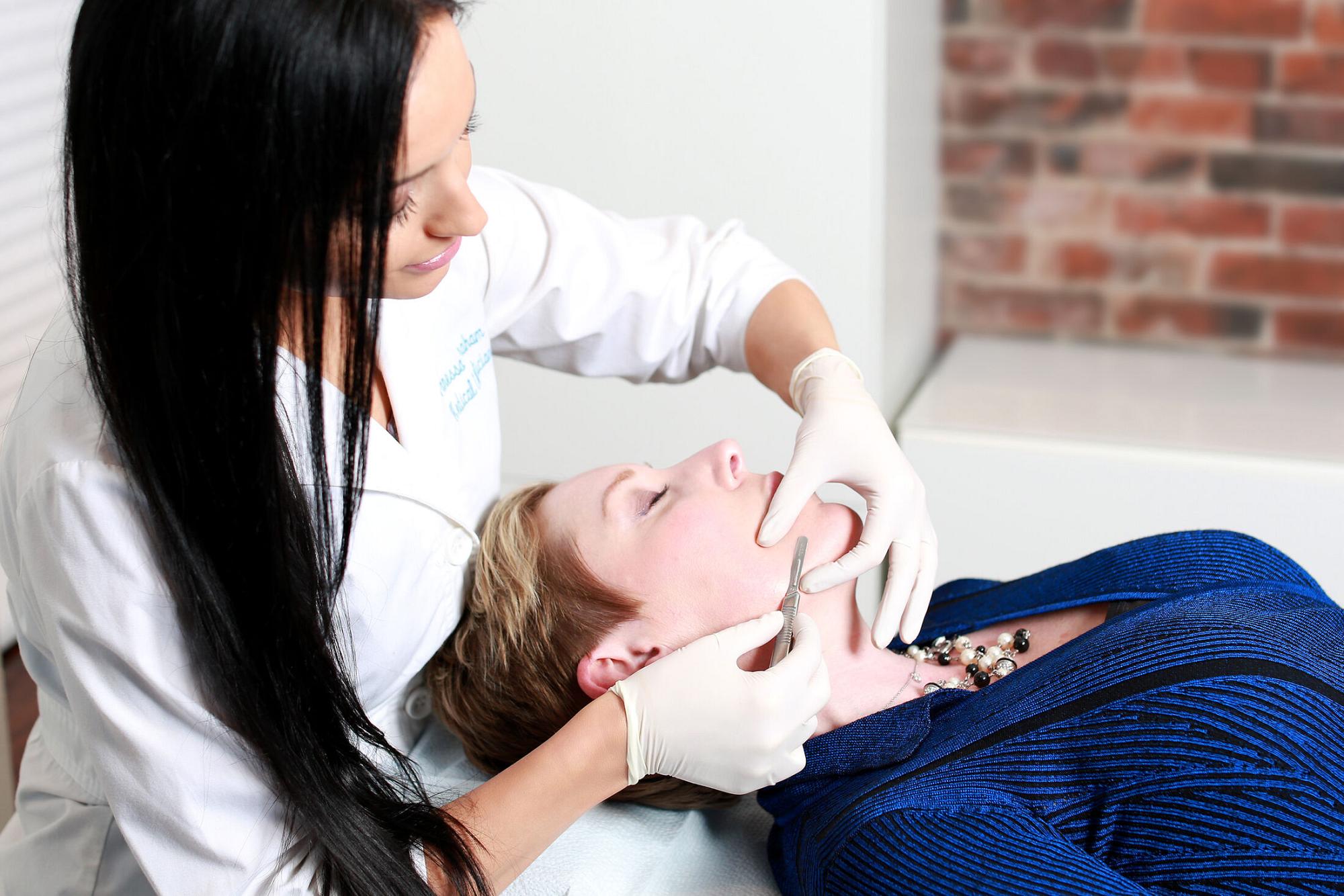 patient model laying on an operating bed receiving dermaplaning in boston by board certified nurse practitioner